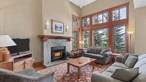 Una sala de estar con chimenea, ventanas amplias y un rincón de descanso acogedor.