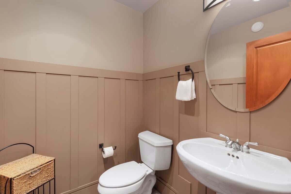 Une salle de bain avec des toilettes, un lavabo et un miroir.