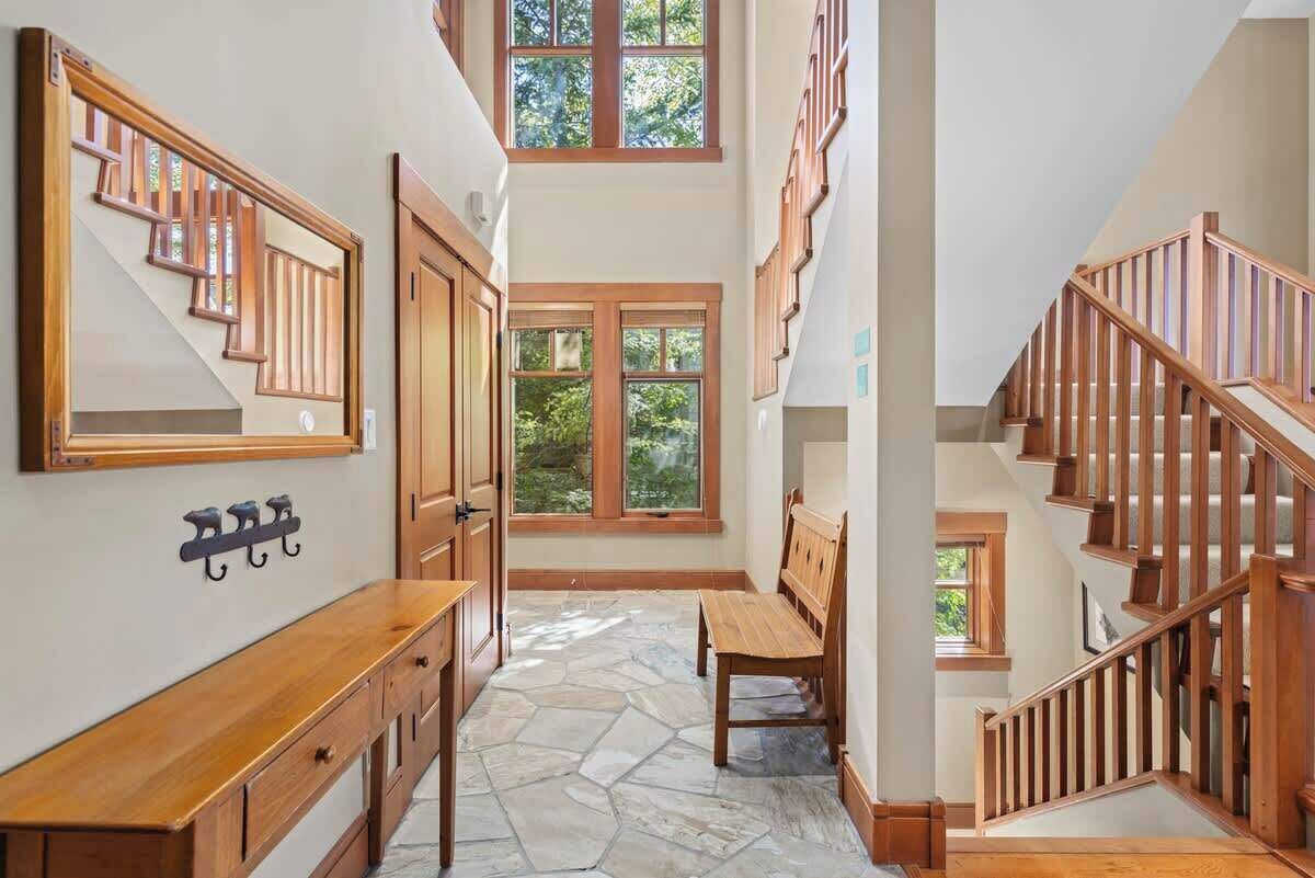 A spacious hallway with a wooden bench, a coat rack, and a staircase with wooden railings.