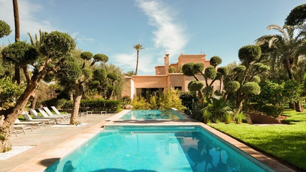 A swimming pool with a clear blue water, surrounded by well-maintained greenery and palm trees. - Private Modern Home 11 Rooms, Only 7min city centre (Marrakech)