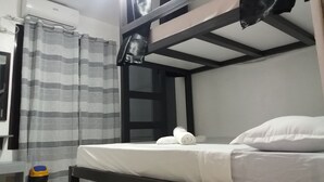 Ein Einzelbett mit weißer Bettwäsche, einem gestreiften Vorhang und einem schwarzen Kopfteil.
