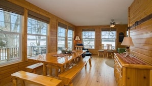 L'intérieur d'un chalet en bois, avec une grande table à manger, des bancs et une cheminée.