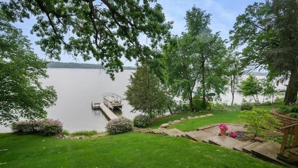 Un jardin paisible au bord du lac, avec une jetée qui s’avance sur l’eau, entouré d’une végétation luxuriante et d’une pelouse bien entretenue.