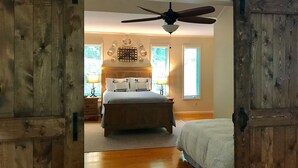 Ein Schlafzimmer mit einem Bett, einem Deckenventilator und einer rustikalen Holztür.