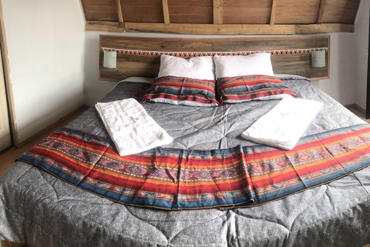 Una cama con un edredón estampado, almohadas y un cabecero de madera.