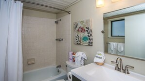 A bathroom with a bathtub, toilet, and sink. There is a shower curtain, a towel rack, and a painting on the wall. - Escape to Bearadise - Close to Slopes, Shuffleboard, Fireplace, BBQ (Big Bear Lake)