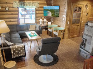 A cozy log cabin interior with a sofa, armchair, dining table, and a fireplace. - Kilpis-arkki by Interhome (Enontekiö)
