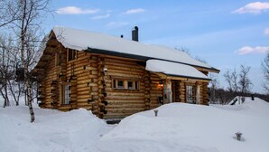 A log cabin with a snow-covered roof, surrounded by snow.