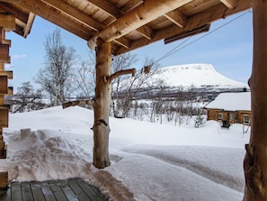 Una cabaña de madera con un paisaje nevado y una montaña al fondo.