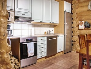 Una cocina con armarios blancos, electrodomésticos de acero inoxidable y una pared de troncos de madera.