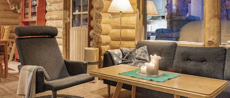 Ein gemütliches Blockhaus-Interieur mit einer Couch, einem Sessel und einem Tisch mit Kerzen.
