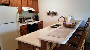 Una cocina con gabinetes de madera, un refrigerador blanco, una estufa y un lavamanos.