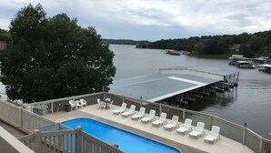 Zona de piscina con sillones de descanso y vistas a un río con muelles.