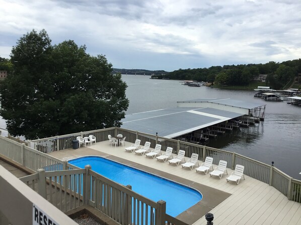 A pool area with lounge chairs and a view of a river with docks.
