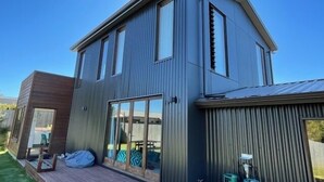 Una casa moderna de dos pisos con amplios ventanales, una terraza y un garaje.