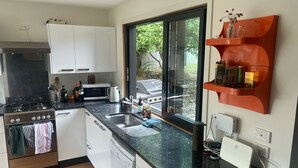 Una cocina moderna con estufa a gas, microondas y lavavajillas. Hay una ventana con vistas al exterior y una encimera con diversos utensilios de cocina.