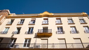 A multi-story building with balconies, windows, and a yellow facade. - Tetuan 3I - Two Bedroom Apartment, Sleeps 4 (Sevilla)