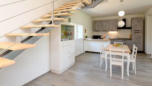 Eine moderne Küche mit einer Holztreppe, weißen Schränken und einem Essbereich mit Tisch und Stühlen.