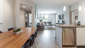 A modern kitchen with a wooden dining table, built-in dishwasher, and a large island with a sink.