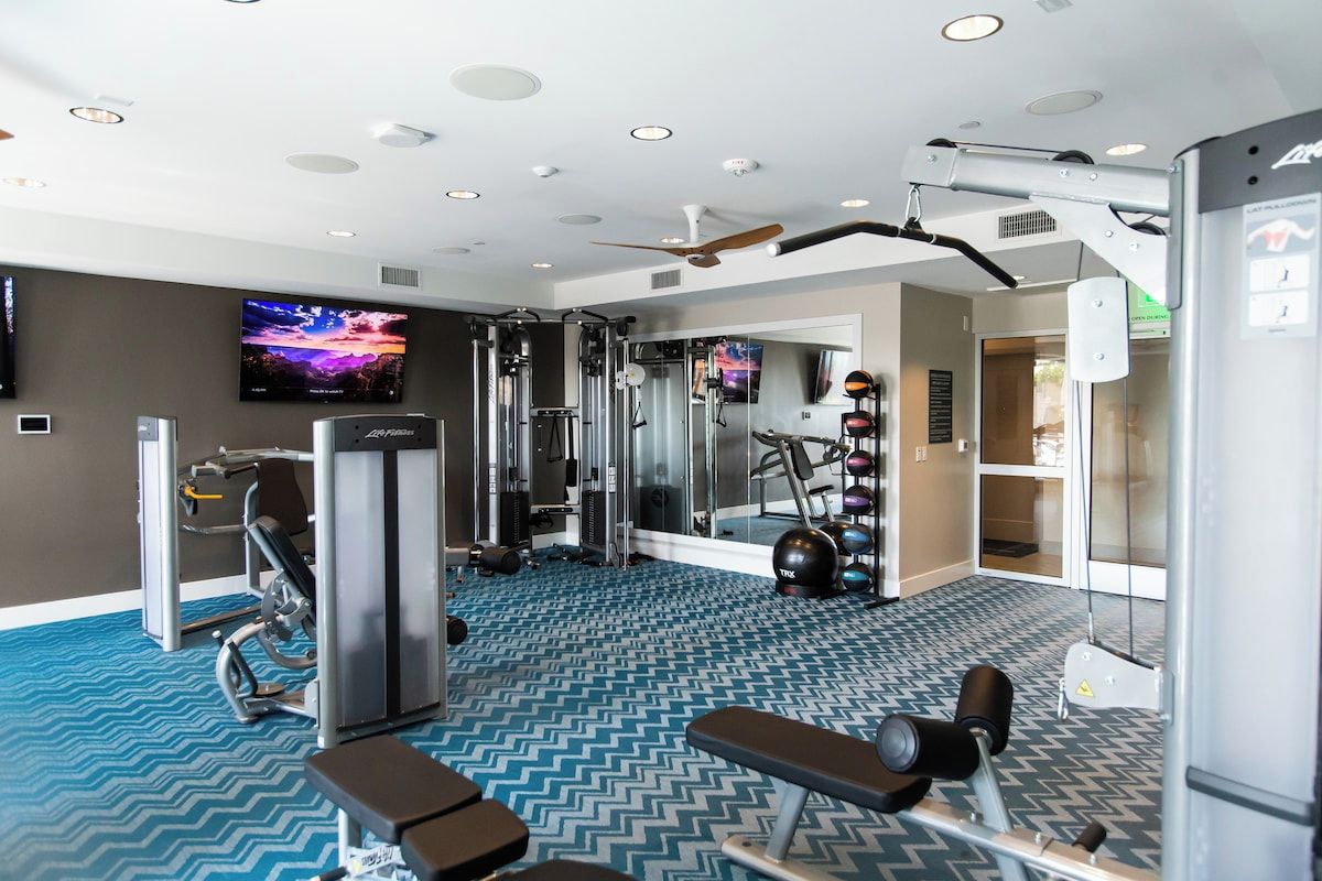 Spacious fitness center with weight machines, cardio equipment and TVs