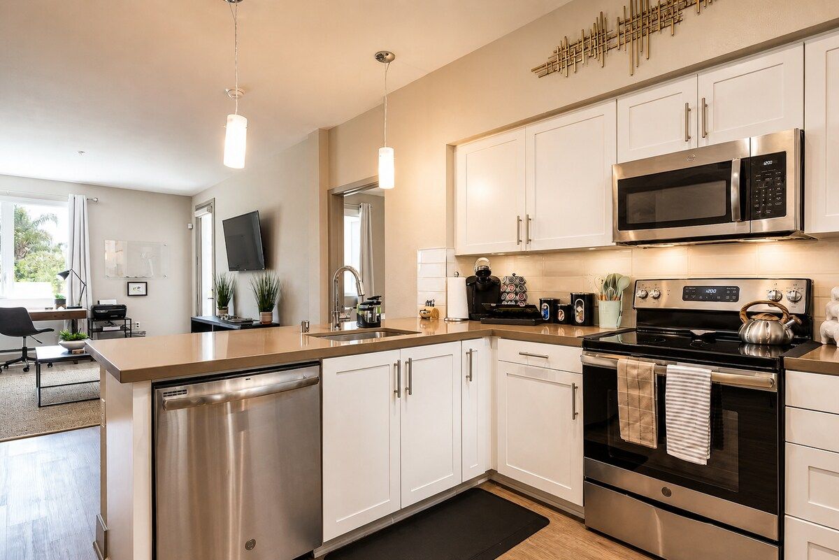 A modern kitchen with stainless steel appliances, white cabinetry, and pendant lighting.