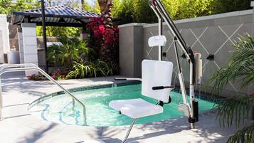 A poolside area with a pool, a chair, and a metal ladder.