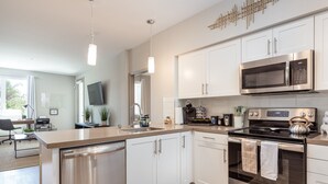 A modern kitchen with stainless steel appliances, white cabinetry, and pendant lighting.