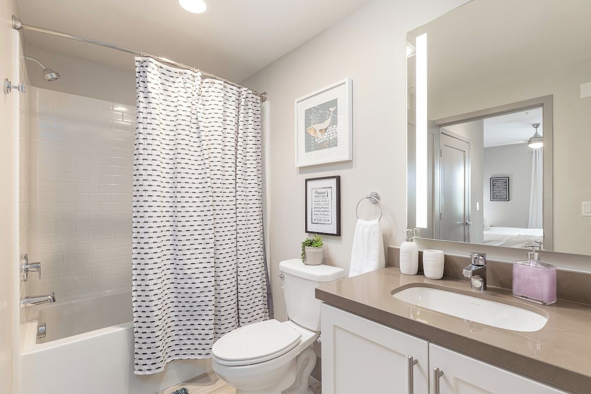 Clean full bathroom with a shower-tub combo and bright vanity