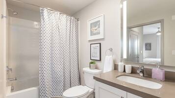 Clean full bathroom with a shower-tub combo and bright vanity