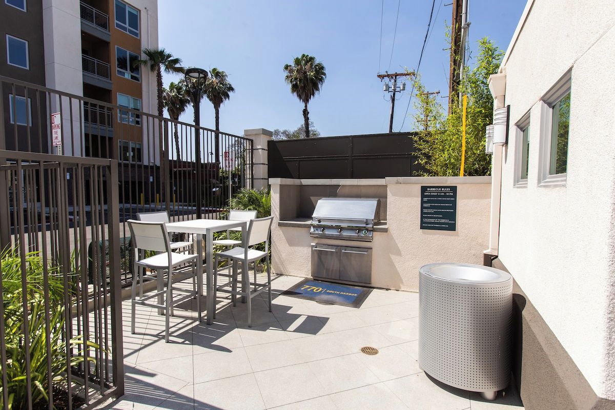 Un espace extérieur aménagé avec un barbecue, des sièges et une poubelle.
