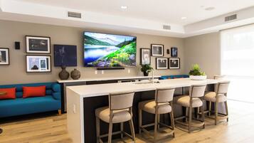 Community clubhouse bar and kitchen with island seating and a TV