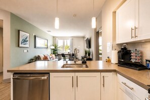 Open kitchen with a breakfast peninsula flowing into the living area - Resort-Style 2bed Condo 3 Miles to Disney (Fullerton)