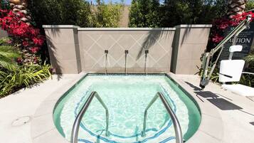 Una piscina con borde de azulejos, una escalera metálica y una pared con un letrero de advertencia.