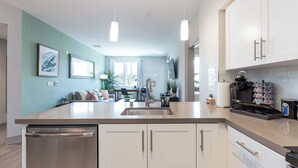 A modern kitchen with a stainless steel dishwasher, white cabinets, and a coffee maker.