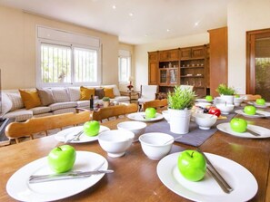 A dining area with a wooden table set for a meal, surrounded by a cozy living room with a sofa and a cabinet.