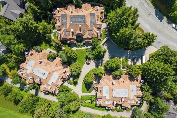 An aerial view of a residential area with multiple houses, roads, and greenery.