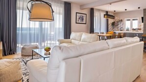 A modern living room with a white sofa, a dining area, and a kitchen in the background. - Vacation home A.R.T. by Interhome (Labin)