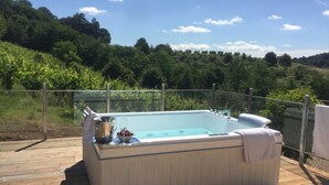 Un jacuzzi en una terraza de madera con vista a una ladera boscosa.