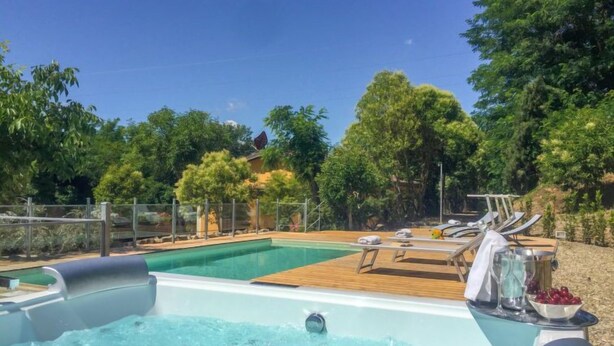 Una piscina con muelle de madera y sillas de descanso.