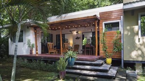 A modern house with a covered porch, outdoor seating, and potted plants. - Eco Casita 3.2 - Casa de Olas (Hacienda Iguana)