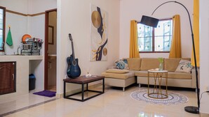 Una sala de estar con un sofá, una mesa de centro, una guitarra y un cuadro en la pared.