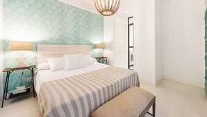 A bedroom with a bed, bedside tables, a bench, and a hanging light fixture. - Genteel Home Velazquez II (Madrid)