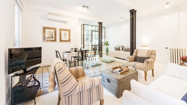 A modern living room with a flat-screen TV, striped armchairs, a coffee table, and a sofa. - Genteel Home Velazquez II (Madrid)