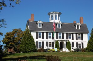 A large, two-story building with a prominent tower and multiple chimneys.