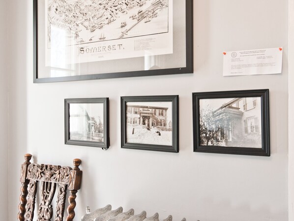 A wall with three framed black-and-white photographs depicting historical buildings and a detailed map of Somerset, MA.