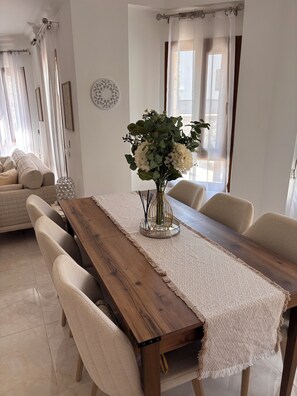 A dining area with a wooden table, beige chairs, and a vase with flowers. - Charming 3/4 bedroomed Villa with private pool and stunning rooftop terrace (Kalkan)