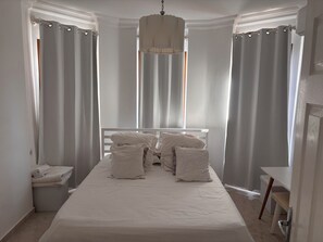 A bedroom with a bed, curtains, a bedside table, and a hanging light fixture. - Charming 3/4 bedroomed Villa with private pool and stunning rooftop terrace (Kalkan)