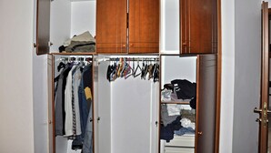 A walk-in closet with wooden cabinets, hanging clothes, and a rack of belts. - 4-rooms 145m3  ap. Seaside Athens: Glifada (Glifada)