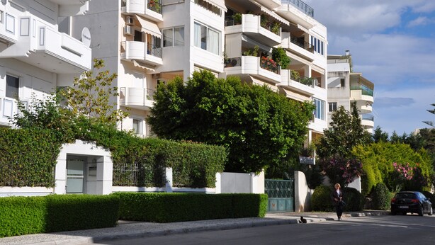 A multi-story residential building with balconies, a gated entrance, and a well-maintained hedge. - 4-rooms 145m3  ap. Seaside Athens: Glifada (Glifada)