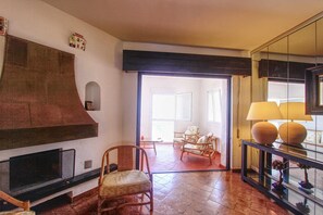 A spacious living area with a fireplace, comfortable seating, and a glass coffee table.